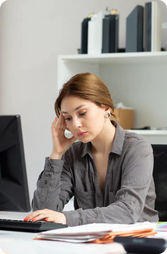 Back-office staff working heads-down at a desk piled with paperwork